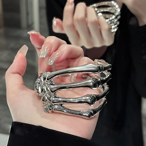 Detailed close-up of a silver skull hand cuff bracelet worn on a model's wrist