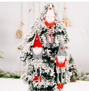 Three Christmas gnomes with long legs hanging on a snowy tree for festive holiday decor