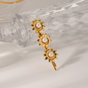 Detail of 18K gold plated sunflower hair clip with white pearls on a glass surface