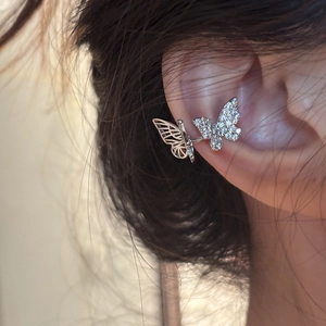 Detailed view of silver butterfly ear cuff set with white zircons on a model's ear