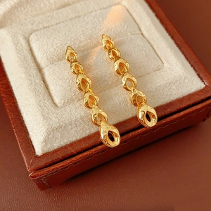 Détail de boucles d'oreilles épi de blé dorées martelées dans un écrin en velours