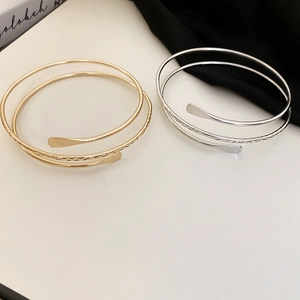 Detail of layered spiral open cuff bracelets in gold and silver with hammered texture