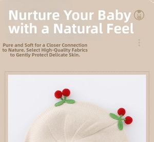 Close-up of beige knit baby beret featuring cute red cherry ornaments and soft texture
