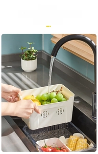 Close-up of divided fridge storage box with drain basket under running water faucet
