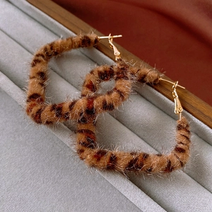 Macro shot of brown leopard print flocked hoop earrings in a gray velvet jewelry box