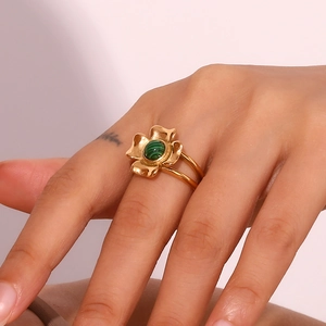 Detail of 18K gold-plated vintage four-petal flower ring with green stone on model finger