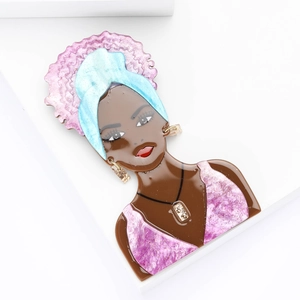 Detail of acrylic African girl brooch featuring colorful headwrap and metallic jewelry