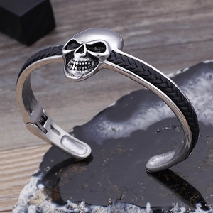 Detail eines Punk-Schädel-Armbands aus silbernem Edelstahl und schwarzem geflochtenem Leder