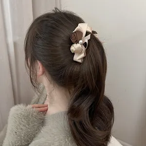 Close-up of vintage satin rose banana clip with pearl on a low ponytail hairstyle