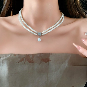 Detail of double-layer pearl necklace with a square blue stone and teardrop pearl drop
