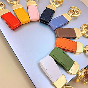 Colorful leather keychains with golden metal hooks arranged on a laptop surface