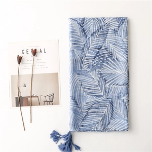 Detail of blue palm leaf print shawl with fringe tassels and rustic cotton linen texture