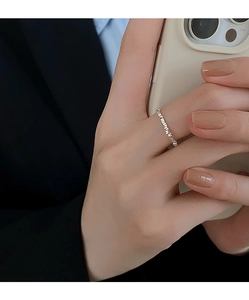 Detail of a silver square geometric ring worn on index finger with textured silver band