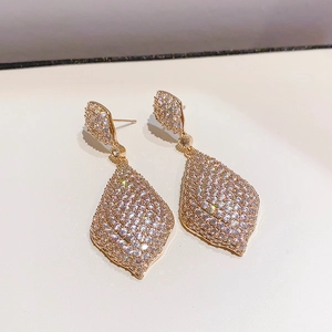 Gros plan de boucles d'oreilles gouttes dorées avec zircons pavés et détails géométriques