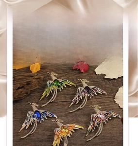 Detail shot of phoenix brooches set with vibrant rhinestones and colorful enamel inlays