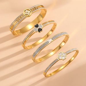 Detailed macro view of gold-plated clover and heart bracelets with zircon inlay