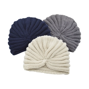 Detail of knit turban hats in cream, navy, and grey showing textured yarn stitching