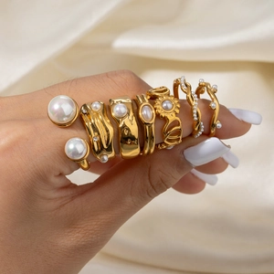 Set of gold stainless steel rings with white pearls and rhinestones on beige satin fabric