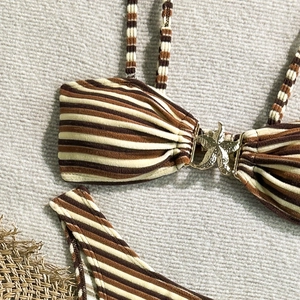 Detail of striped bikini top featuring a golden starfish buckle and ribbed texture fabric