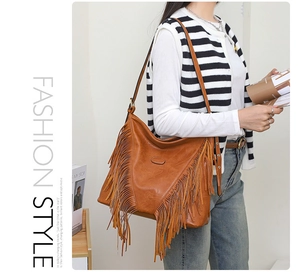 Détail d'un sac bandoulière caramel en cuir avec de longues franges décoratives