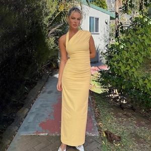 Elegant one shoulder pleated maxi dress in pale yellow, low-angle outdoor fashion shot