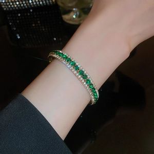 Close-up of golden emerald bracelet with green stones and sparkling zircon accents