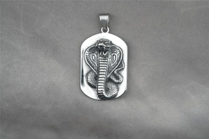 Macro shot of silver stainless steel pendant with embossed cobra snake relief detail