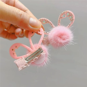 Close-up of pink faux fur rabbit ear hair clips with rhinestones and metal crocodile grip