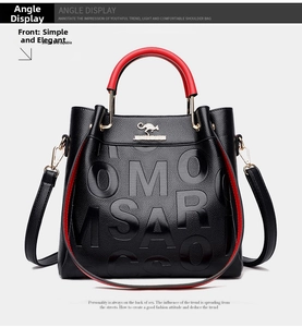 Detail of black pebble leather tote with red handles and gold kangaroo logo emblem