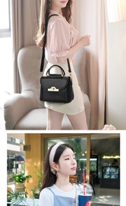 Detail of black leather handbag with a gold metal handle and round swivel lock closure