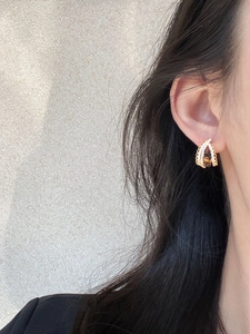 Detail view of gold hoop earrings with brown tiger eye stone and sparkling crystals