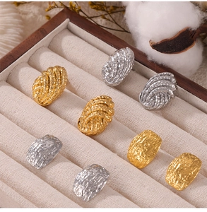 Gros plan sur des boucles d'oreilles en titane texturé or et argent dans un écrin en bois