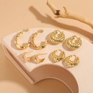 Detail of four pairs of 14K gold plated geometric hollow earrings on a minimal stand