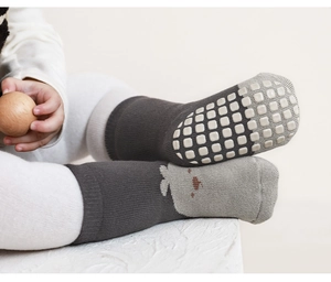 Macro detail of baby floor socks featuring white non-slip grippers on the padded soles