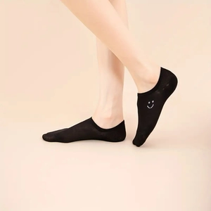 Detail of black invisible low-cut sock featuring a white embroidered smile on thin fabric