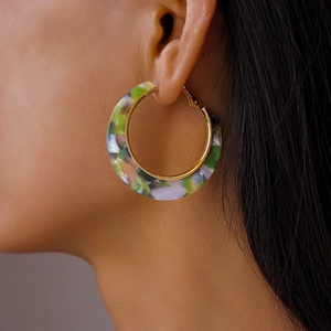 Close-up of model wearing C-shaped acetate hoop earrings with colorful marble pattern