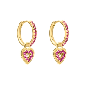 Gros plan sur boucles d'oreilles cœur en or serties de zircones roses sur fond blanc