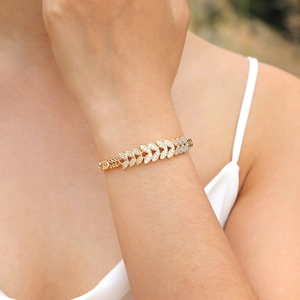 Detailed close-up of a gold wheat leaf bracelet with micro-pave white zircon crystals