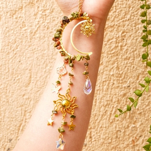 Detail of golden crescent moon suncatcher with raw green crystals and star charms