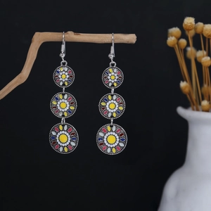Close-up of Bohemian tiered floral tassel earrings with colorful beads on a branch