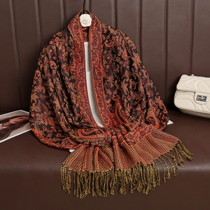 Ethnic paisley cashmere feel scarf in reddish brown with fringe on a leather surface