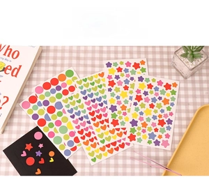 DIY colorful stickers in star, heart, and circle shapes with pink tweezers on plaid background
