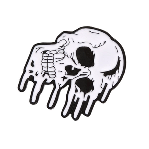 Close-up of a melting skull enamel pin in black and white finish for gothic apparel
