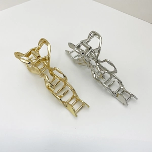 Detail view of large gold and silver metal hair claws with elegant hollow twisted design