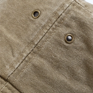 Detail of washed cotton fabric with metal eyelets and double-stitched seams on outdoor bucket hat