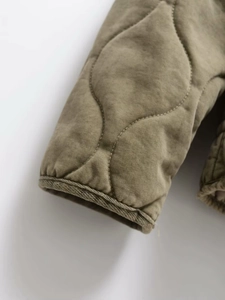 Detail view of military green quilted jacket featuring diamond stitching and finished cuffs