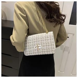 Close-up of white tweed shoulder bag with golden chain strap on a khaki blazer