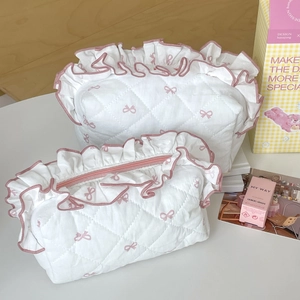 Detail of white quilted cosmetic bags with pink bow pattern and ruffled edge decor