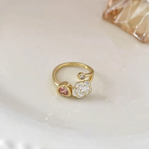 Anello aperto dorato con camelia bianca e zircone a cuore rosa su vassoio