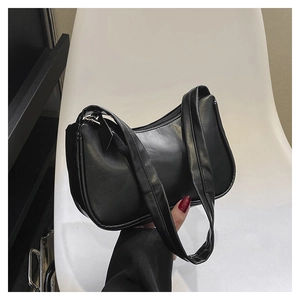 Close-up of black leather hobo shoulder bag featuring minimalist half-moon zipper design